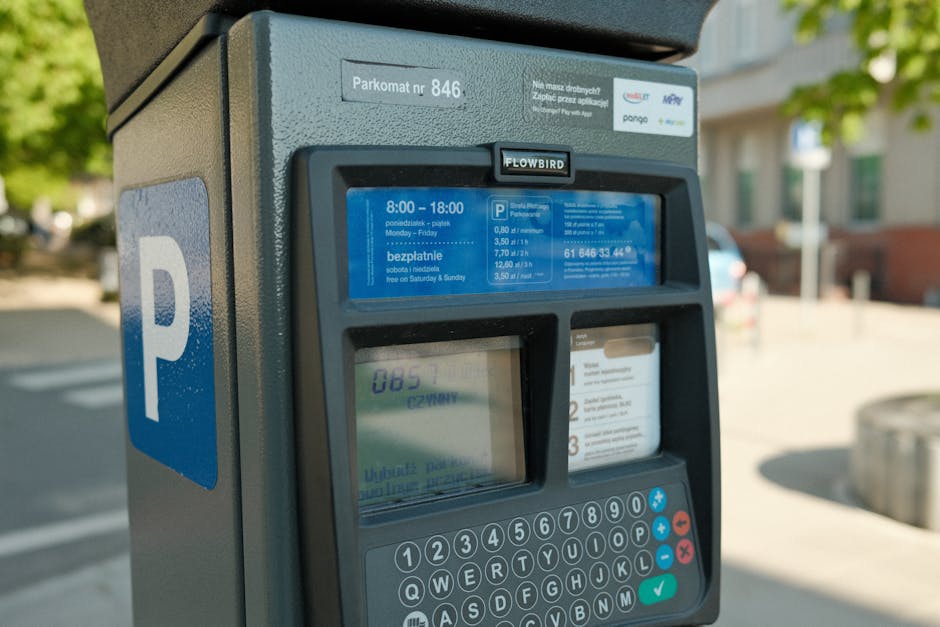 Close-up image of a parking meter located outdoors on a city street, with a large blue 'P' sign indicating available parking. The parking meter features a digital display showing parking fees and time