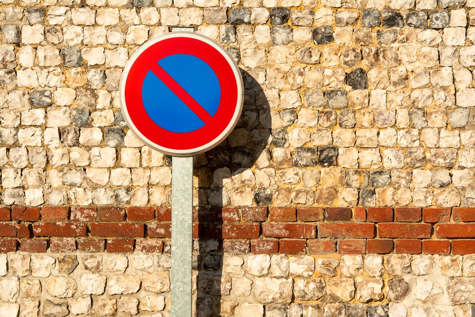 A vertical signpost displaying a reserved parking notice with a blue wheelchair symbol indicating accessible parking for disabled persons and a label stating 'VAN ACCESSIBLE' beneath it. The sign is m